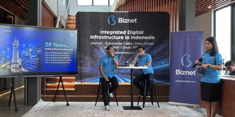 26 Tahun Biznet, Perkuat Infrastruktur Digital dan Hadirkan Inovasi Berbasis AI  SEMARANG – Memasuki usia ke-26 tahun, Biznet terus memperkuat perannya dalam mendukung transformasi digital Indonesia melalui pengembangan infrastruktur jaringan, pusat data berbasis kecerdasan buatan atau Artificial Intelligence (AI), hingga inovasi layanan pelanggan. Langkah ini menjadi bagian dari komitmen perusahaan untuk menghadirkan konektivitas yang andal sekaligus membuka lebih banyak peluang bagi masyarakat di era digital.  Selama lebih dari dua dekade, Biznet tidak hanya berfokus pada pembangunan jaringan internet, tetapi juga mengembangkan infrastruktur yang mampu menjawab kebutuhan teknologi masa depan. Sejumlah langkah strategis dilakukan, mulai dari pengoperasian AI-Ready Data Center di Bali hingga pengembangan jaringan kabel serat optik bawah laut Biznet Nusantara Cable System (BNCS) untuk memperkuat konektivitas antarpulau.  Kebutuhan terhadap infrastruktur digital berkapasitas besar semakin meningkat seiring pesatnya adopsi teknologi. Berdasarkan PwC Global Workforce Hopes & Fears Survey 2025, sebanyak 69 persen pekerja di Indonesia telah menggunakan AI untuk pekerjaan mereka dalam 12 bulan terakhir. Sementara itu, survei Asosiasi Penyelenggara Jasa Internet Indonesia (APJII) mencatat penetrasi internet Indonesia mencapai 81,72 persen pada 2026.  Perkembangan tersebut mendorong kebutuhan terhadap konektivitas yang tidak hanya cepat, tetapi juga didukung kapasitas komputasi dan pengolahan data yang semakin besar. Untuk menjawab tantangan tersebut, Biznet menghadirkan Biznet AI Center di Bali sebagai AI-Ready Data Center pertama milik perusahaan.  Fasilitas ini dirancang untuk mendukung kebutuhan komputasi berintensitas tinggi, terutama dalam menjalankan server AI. Berbeda dari pusat data konvensional, AI Center dilengkapi kapasitas daya listrik yang lebih besar, teknologi pendingin cair atau liquid cooling, serta konektivitas yang andal. Infrastruktur tersebut memiliki kapasitas daya hingga 145 kW per rak dan dilengkapi laboratorium pengembangan AI.  Kehadiran fasilitas ini diharapkan dapat menjadi fondasi bagi perkembangan ekosistem kecerdasan buatan di Indonesia. Dengan dukungan infrastruktur yang sesuai, pelaku usaha dan pelanggan dapat mengoptimalkan pemanfaatan teknologi AI untuk meningkatkan produktivitas, mengembangkan inovasi, serta mempercepat proses pengolahan data.  President Director Biznet, Adi Kusma, mengatakan bahwa perjalanan 26 tahun perusahaan menjadi momentum untuk terus menyesuaikan layanan dengan perkembangan kebutuhan masyarakat digital.  “Selama 26 tahun mendukung transformasi digital Indonesia, dalam perjalanannya, kami terus berupaya untuk dapat menjawab kebutuhan masyarakat digital. Kami memahami betul bahwa saat ini kebutuhan digital tidak terbatas pada konektivitas semata, namun juga kapasitas besar untuk mengakselerasi segala kegiatan komputasi dan pengolahan data yang lebih besar untuk mendukung implementasi AI yang sedang berkembang saat ini,” jelas Adi.  Selain memperkuat infrastruktur pusat data, Biznet juga mengembangkan konektivitas antarpulau melalui Biznet Nusantara Cable System (BNCS), jaringan kabel serat optik bawah laut yang dibangun, dimiliki, dan dioperasikan sendiri sejak 2024. Infrastruktur ini menjadi bagian dari upaya perusahaan meningkatkan kapasitas jaringan sekaligus mendukung pemerataan akses internet berkualitas di Indonesia.  Biznet kini menyiapkan pembangunan jaringan kabel bawah laut baru, yakni Biznet Nusantara Cable System-2 (BNCS-2). Jaringan tersebut direncanakan menghubungkan Surabaya di Pulau Jawa, Banjarmasin di Kalimantan, Sumenep di Madura, serta Buleleng di Bali.  Pengembangan BNCS-2 diharapkan mampu meningkatkan kecepatan dan kualitas layanan di wilayah yang terhubung. Bagi Biznet, pembangunan jaringan bawah laut bukan sekadar menghubungkan satu wilayah dengan wilayah lainnya, melainkan juga menciptakan infrastruktur yang mendukung pertumbuhan aktivitas ekonomi dan membuka kesempatan lebih luas bagi masyarakat.  “Kami percaya bahwa membangun jaringan bukan hanya tentang menghubungkan satu titik wilayah dengan wilayah lainnya. Karena itu, infrastruktur yang kami bangun seperti Biznet Nusantara Cable System ini diharapkan mampu menciptakan pengalaman layanan yang lebih optimal bagi pelanggan serta membuka lebih banyak peluang dan kesempatan di era digital saat ini,” tambah Adi.  Sejalan dengan penguatan infrastruktur utama, Biznet terus memperluas jangkauan jaringan ke berbagai daerah. Saat ini, jaringan perusahaan telah menjangkau lebih dari 200 kota dan kabupaten di Pulau Jawa, Bali, Sumatra, Bangka, Batam, Kalimantan, Sulawesi, dan Flores. Jangkauan tersebut didukung lebih dari 3 juta homepass serta lebih dari 300 kantor cabang untuk mendekatkan layanan kepada pelanggan.  Komitmen memperluas akses digital juga diwujudkan melalui program tanggung jawab sosial perusahaan atau Corporate Social Responsibility (CSR). Pada 2026, Biznet memberikan layanan internet gratis kepada lebih dari 300 kepala keluarga di sekitar lokasi Biznet MarinePOP, yakni titik pendaratan kabel bawah laut perusahaan. Program tersebut menjangkau masyarakat di Kabupaten Jembrana, Kabupaten Serang, Kabupaten Karawang, dan Kabupaten Gresik.  Melalui inisiatif ini, Biznet berupaya agar manfaat pembangunan infrastruktur digital dapat dirasakan tidak hanya oleh pelanggan, tetapi juga oleh masyarakat yang tinggal di sekitar fasilitas jaringan. Akses internet diharapkan dapat membantu warga memperoleh informasi, mendukung kegiatan belajar, menjalankan pekerjaan, serta membuka peluang pengembangan ekonomi di lingkungan masing-masing.  “Bagi kami konektivitas bukan hanya tentang menyediakan akses Internet, tetapi juga membuka kesempatan bagi masyarakat untuk belajar, bekerja, mendapatkan informasi, dan berkembang di era digital saat ini. Karena itu, melalui program CSR ini, kami ingin menghadirkan manfaat konektivitas secara lebih luas, khususnya bagi masyarakat di sekitar infrastruktur Biznet. Inisiatif ini menjadi bagian dari komitmen kami untuk terus membangun infrastruktur digital yang tidak hanya menghubungkan lebih banyak orang, tetapi juga menciptakan peluang dan memberikan nilai lebih bagi setiap individu,” lanjut Adi.  Di sisi pengalaman pelanggan, Biznet terus mengembangkan MyBiznet App sebagai sarana untuk memudahkan pengguna mengelola layanan, memperoleh informasi, mengakses berbagai promosi, hingga mendapatkan dukungan layanan pelanggan. Aplikasi tersebut juga terus dikembangkan dengan pemanfaatan teknologi AI agar informasi dan solusi yang dibutuhkan pelanggan dapat diberikan secara lebih cepat, responsif, dan personal.  Sebagai bentuk apresiasi atas kepercayaan pelanggan, Biznet menghadirkan program Biznet Prize Vaganza yang memberikan kesempatan kepada pelanggan Biznet Home dan Biznet Metronet untuk memperoleh berbagai hadiah. Hadiah yang ditawarkan mencakup merchandise eksklusif Biznet, Apple Watch, iPad, PlayStation 5, voucher menginap di Rimba by AYANA Bali, MacBook Neo, hingga hadiah utama berupa emas seberat 10 gram, 25 gram, dan 100 gram.  Khusus dalam rangka perayaan ulang tahun ke-26 pada Oktober 2026, Biznet juga memberikan peningkatan kapasitas bandwidth menjadi 100 Mbps selama satu bulan tanpa biaya tambahan bagi pelanggan Biznet Home. Program ini menjadi bagian dari upaya perusahaan untuk menghadirkan konektivitas berkapasitas besar sekaligus memberikan pengalaman internet yang semakin optimal.  “Bagi kami, 26 tahun bukan hanya tentang seberapa jauh kami melayani masyarakat, tetapi juga tentang apa yang dapat kami berikan ke depannya. Karena itu, kami akan terus berinvestasi pada infrastruktur, teknologi, dan pengalaman pelanggan untuk menciptakan lebih banyak nilai serta mendukung Indonesia menjadi semakin terhubung,” tutup Adi.  Memasuki usia ke-26 tahun, Biznet menegaskan komitmennya untuk terus berinovasi melalui pengembangan infrastruktur, perluasan jaringan, dan peningkatan kualitas layanan. Dengan menggabungkan konektivitas, kesiapan infrastruktur AI, serta program yang memberikan manfaat langsung kepada masyarakat, Biznet berupaya mengambil bagian dalam membangun ekosistem digital Indonesia yang semakin inklusif, produktif, dan siap menghadapi tantangan masa depan.